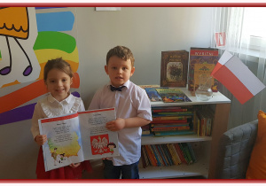 Nikosia i Tomuś w przedszkolnej bibliotece oglądają książkę z wierszami o Polsce